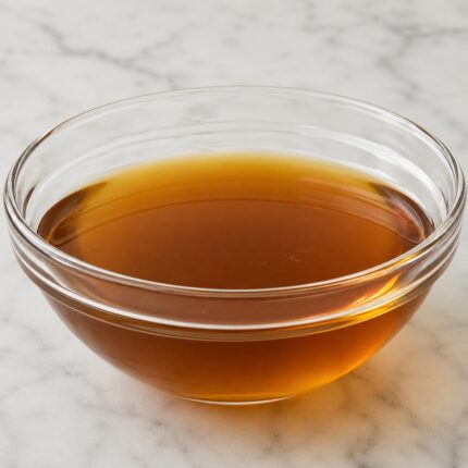 Coco diethanolamide liquid in a clear container, showing its viscous, pale yellow appearance.