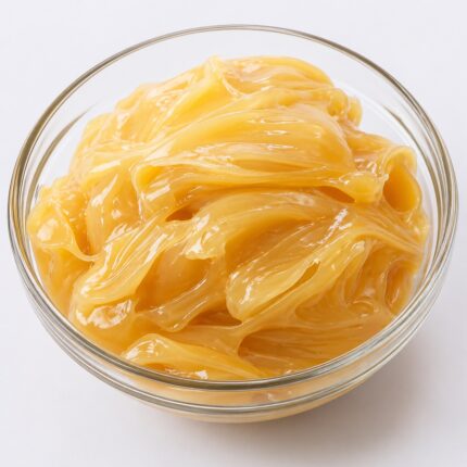 Organic lanolin in a glass container, showing its thick, pale yellow, waxy texture.