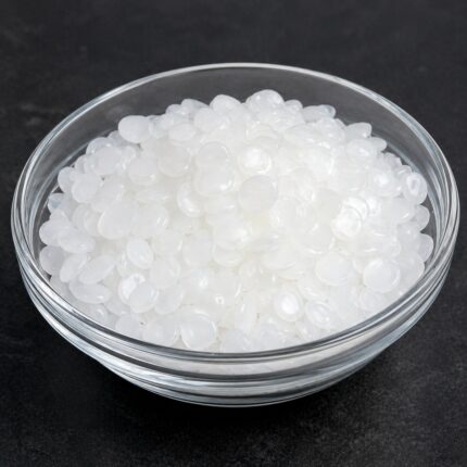 White to yellowish solid blocks or flakes of Ozokerite wax with a firm texture, displayed in a clean container for cosmetic use.