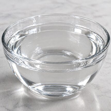 Thioglycolic acid liquid in a glass container, showing its clear, colorless to pale yellow appearance.